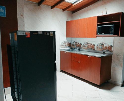 een keuken met rode kasten en een zwarte koelkast bij Habitacion cama doble en sabaneta in Sabaneta