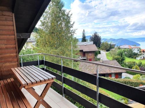 un banco de madera sentado en el balcón de una casa en Elfe-Apartments FerienMietWohnungen, en Emmetten