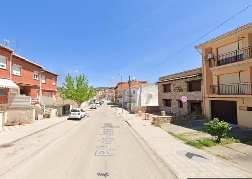 an empty street in a small town with a car at Apartamentos Ohana in Jadraque
