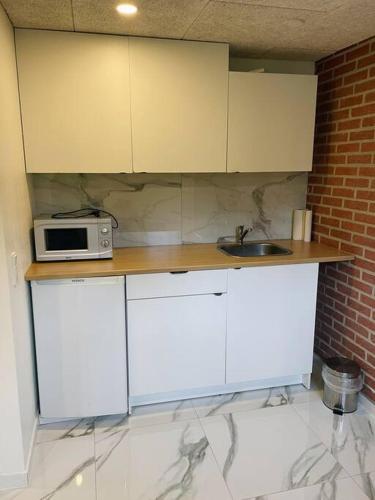una cocina con armarios blancos y microondas en una encimera en Cool private room en Løsning