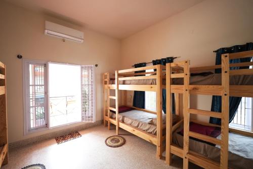 a room with three bunk beds and a window at Palace Hostel by Borrbo in Mysore