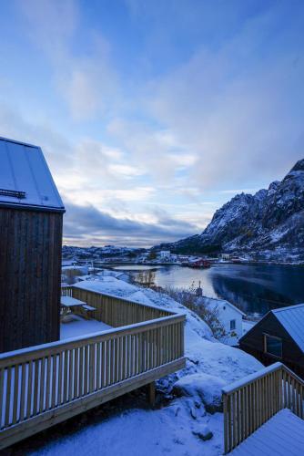 a house with snow on the ground next to a river at Lofoten Cabins in Hopen