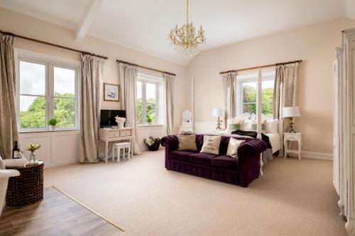 ein Wohnzimmer mit einem lila Sofa und Fenstern in der Unterkunft Downwood Vineyard Manor in Idyllic Countryside in Blandford Forum