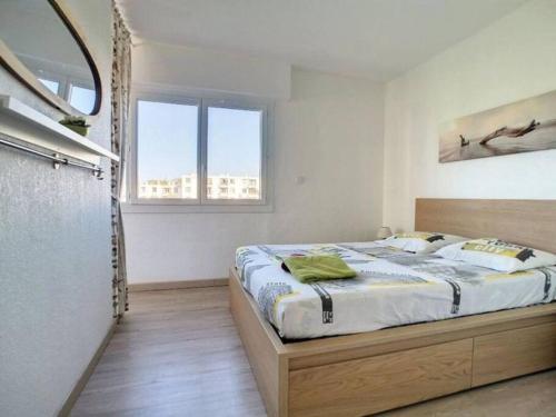 um quarto com uma cama e duas janelas em Appt lumineux avec terrasse cœur de ville 35 m² em Saint-Raphaël