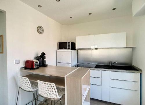 uma cozinha com uma mesa e cadeiras e um frigorífico em Appt lumineux avec terrasse cœur de ville 35 m² em Saint-Raphaël