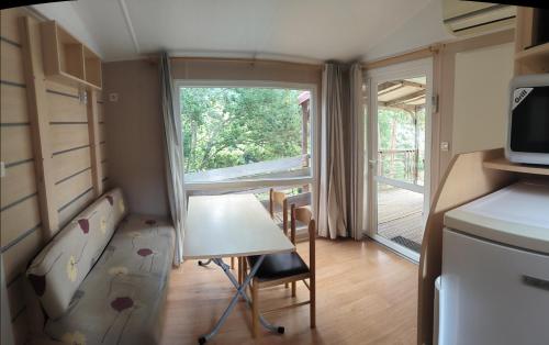 a small room with a table and a kitchen with a window at Mira Monti Location in Belvédère