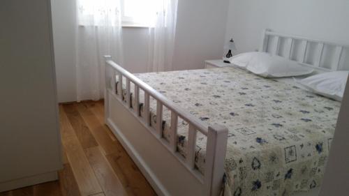 a bedroom with a white bed with a floral bedspread at Apartments Rustic in Biograd na Moru