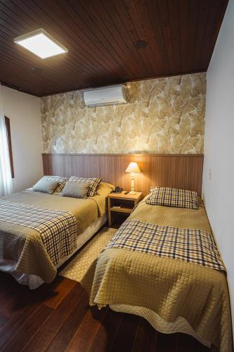 a bedroom with two beds and a lamp on a table at Vila Suzana Parque Hotel in Canela