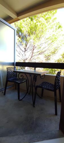 - une table et deux chaises sur une terrasse couverte avec une fenêtre dans l'établissement Les Garriguettes, à Gréoux-les-Bains