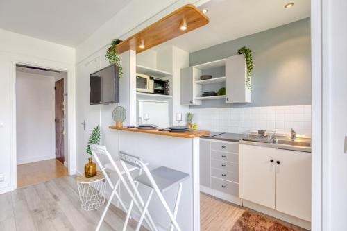 une cuisine avec des armoires blanches et un évier dans l'établissement Zzzen aux portes de Paris avec Parking et Netflix, à Vincennes