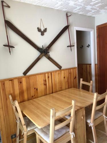a dining room with a wooden table and a clock on the wall at Joli studio in Saint-Étienne-de-Tinée