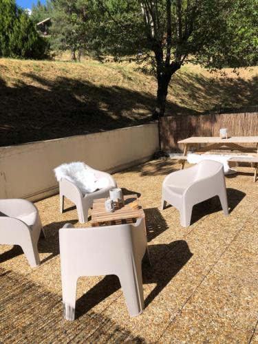 a group of white benches and tables on a patio at Joli studio in Saint-Étienne-de-Tinée