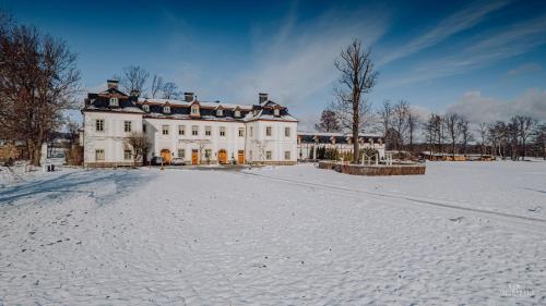 a large white house with snow on the ground at Pałac Pakoszów Schlosshotel Wernersdorf in Jelenia Góra