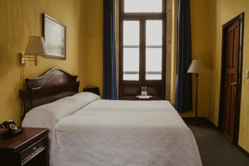 Habitación de hotel con cama y ventana en Hotel Posada San Agustin en Durango