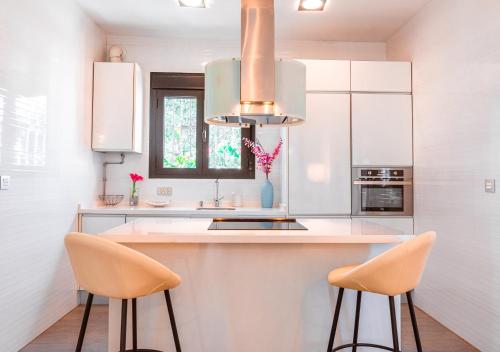 a kitchen with white cabinets and a sink and two chairs at Edomus Gran Plaza Boutique in Seville