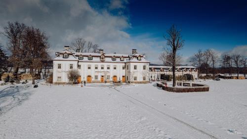a large white house with snow on the ground at Pałac Pakoszów Schlosshotel Wernersdorf in Jelenia Góra