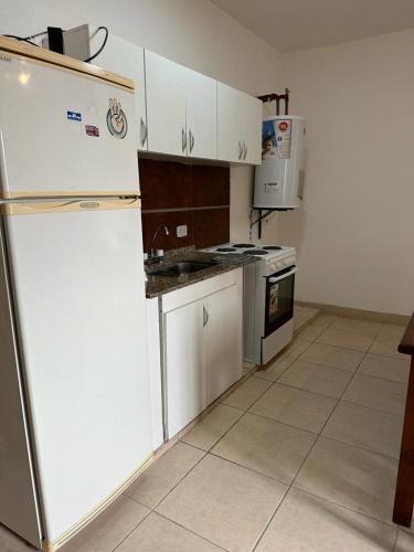uma cozinha com armários brancos, um fogão e um frigorífico em Monoambiente Céntrico2 em Santiago del Estero