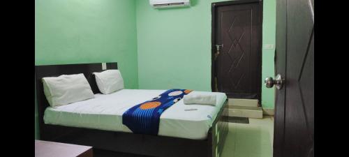 a small bed in a room with green walls at ARUDRA BUDGET suites in Ongole
