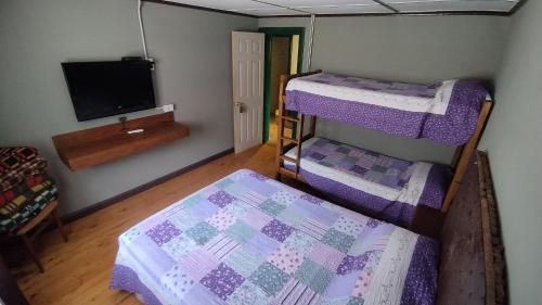 a room with three bunk beds and a flat screen tv at Hospedaje Leñas del Tolosa in Las Cuevas