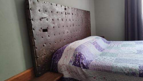 a bedroom with a bed with a metal headboard at Hospedaje Leñas del Tolosa in Las Cuevas