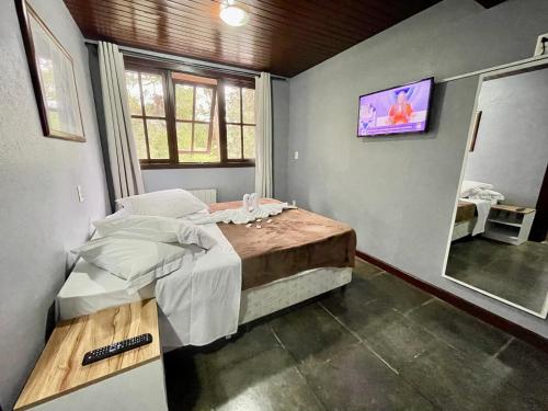 um quarto com uma cama e uma televisão na parede em Pousada Bella Serra em Canela