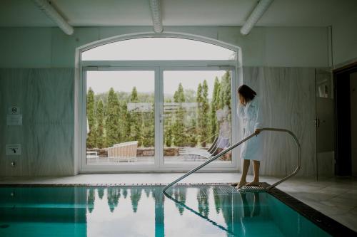 a woman standing next to a swimming pool with a hose at Pałac Pakoszów Schlosshotel Wernersdorf in Jelenia Góra