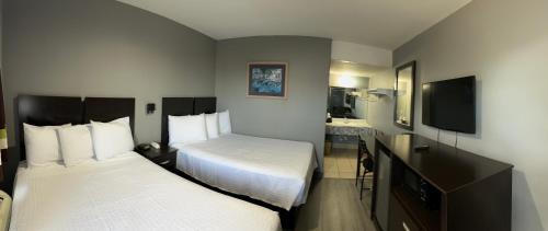 a hotel room with two beds and a flat screen tv at Americas Best Value Inn and Suites Groves in Groves