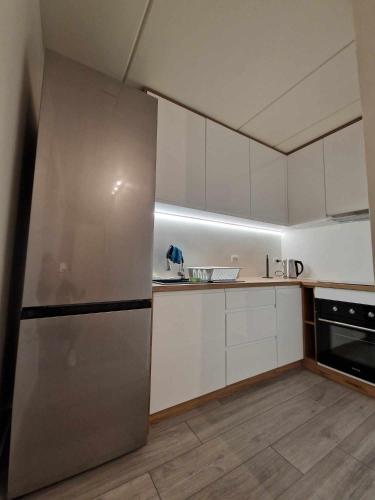 a kitchen with white cabinets and a stainless steel refrigerator at Enkeltværelse med fælles badeværelse in Esbjerg