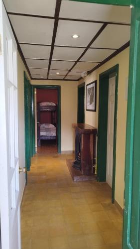 a hallway with a room with green walls and a table at Hospedaje Leñas del Tolosa in Las Cuevas