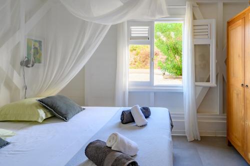 een slaapkamer met een wit bed en handdoeken bij Villa Paruline in Grand-Bourg