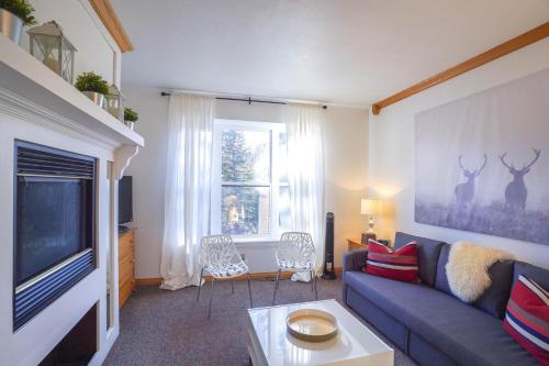 a living room with a blue couch and a tv at Cozy Brian Head Condo Walk to Navajo Express Lift in Brian Head