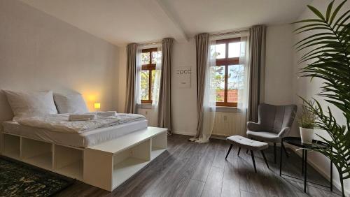 Schlafzimmer mit einem Bett, einem Stuhl und Fenstern in der Unterkunft YourFavoriteBed 90m2 Designwohnung im Zentrum 1 in Zwickau