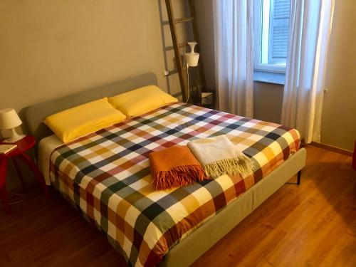 a bed with a plaid blanket and pillows on it at Da Giuditta FreeCarPark&Garden in Domodossola