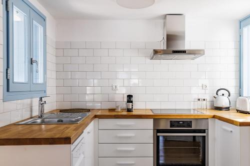 a white kitchen with a sink and a stove at Villa Strada in Skopelos Town
