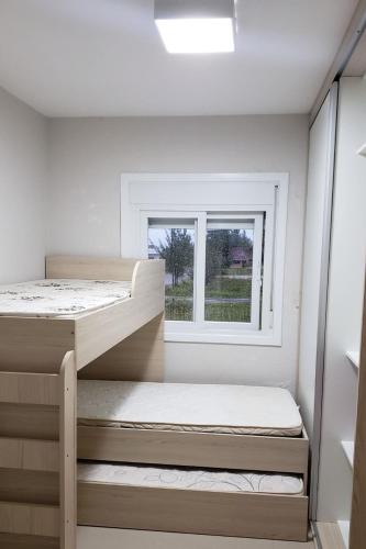 a bedroom with two bunk beds and a window at Sobrados com suíte e sacada vista ao mar in Capão da Canoa