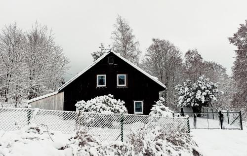 a black barn with snow in front of it at Chata Koza in Bublava