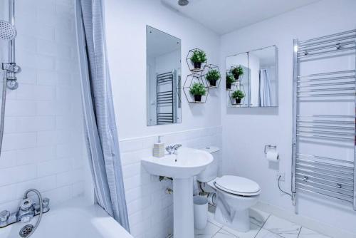 a white bathroom with a sink and a toilet at Grand and Stylish 3BR Apartment in Greater London in London