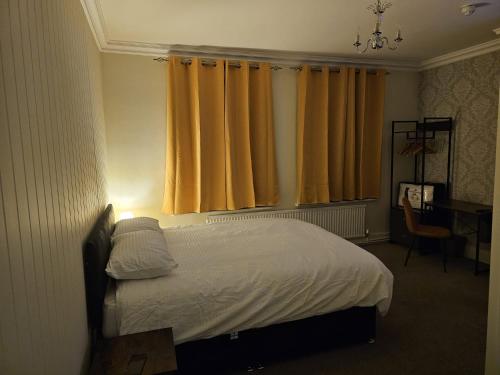 a bedroom with a bed with yellow curtains and a desk at The Market Hotel in Alton