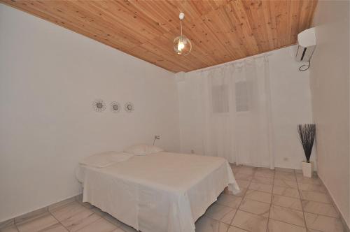 Habitación blanca con cama y techo de madera. en Loca Vacances, en Sainte-Anne