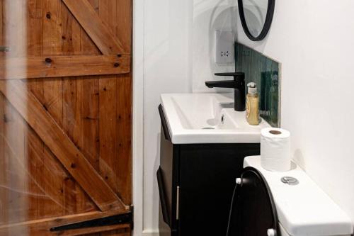 a bathroom with a sink and a wooden door at Stunning 2BD in the Heart of Malmesbury! in Malmesbury