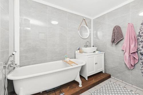 W łazience znajduje się biała wanna i umywalka. w obiekcie Family-friendly home near canal w mieście Spangereid
