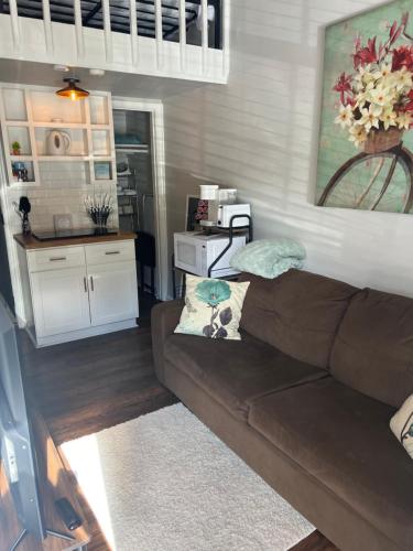 a living room with a brown couch and a kitchen at Poppy Loft in Raleigh