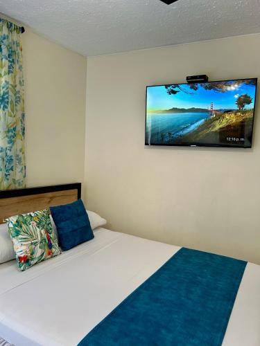 a bedroom with a bed with a flat screen tv on the wall at Hotel Bisou in Cali