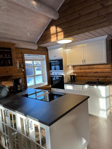 a kitchen with white cabinets and a black counter top at Holiday cottage with sauna close to Kjeragbolten-Bedding included in Tjørhom