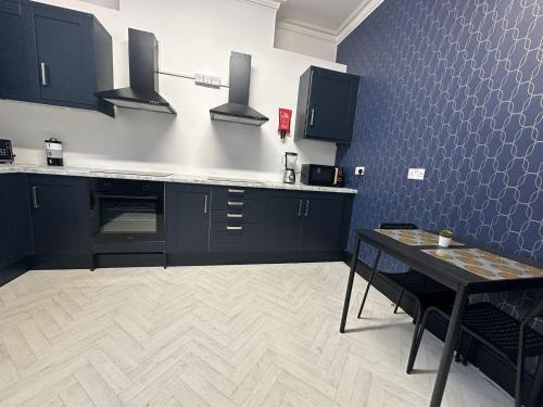 a kitchen with black cabinets and a table in it at 10 Minutes to Central London Vaux in London