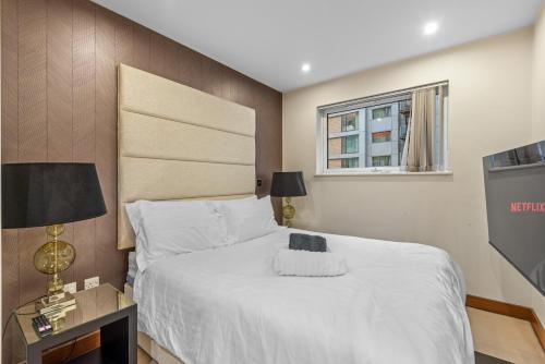 1 dormitorio con 1 cama blanca grande y ventana en Londwell, Chelsea Living, Central Flat with Balcony, en Londres
