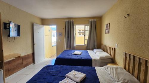 a hotel room with two beds and a television at Pousada Ceará - Porto das Dunas in Aquiraz