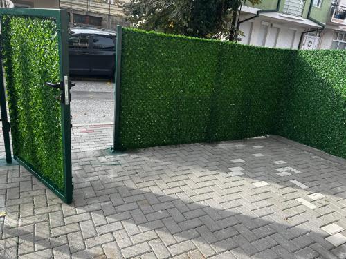 a green fence with a door on a sidewalk at Juliya Apartment in Kavadarci