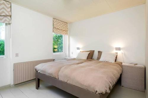 a white bedroom with a large bed with two pillows at Vrijstaand vakantiehuis, 5 minuten lopen van het strand in Zoutelande
