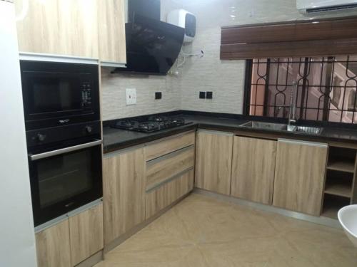 a kitchen with wooden cabinets and a stove top oven at cozy comforts in Lagos